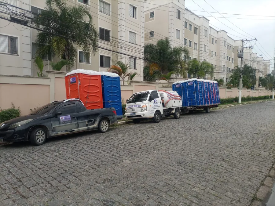 Entrega de banheiros químicos em condomínio, com caminhão e reboque da FR Renovar